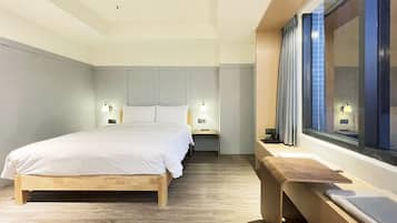 A modern hotel room with a large bed, bedside tables, and a window with curtains.