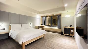 Une chambre d’hôtel moderne avec un grand lit, des tables de chevet, un bureau, un miroir et une armoire.