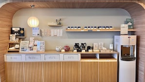 A reception desk with labeled bins for trash, tin cans, paper, and plastic. There are shelves with mugs and a water dispenser. - Green Hotel - midori (Taichung)