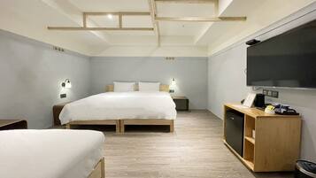 A modern hotel room with a wooden bed, a TV, and a small desk with a lamp.