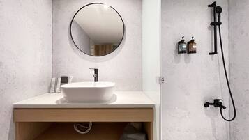 A modern bathroom with a round mirror, a white sink, and a shower area.