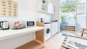 Eine moderne Küche mit Mikrowelle, Wasserkocher und Waschmaschine. Ein Fenster bietet Blick auf Grünflächen.