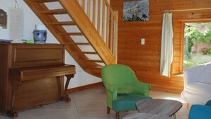 Un escalier en bois, un fauteuil vert, un bureau en bois et un tableau accroché au mur.
