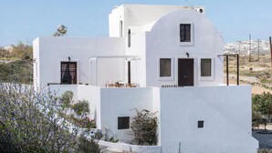 Un edificio blanco con un balcón, un tanque de agua en el techo y vistas del paisaje circundante.