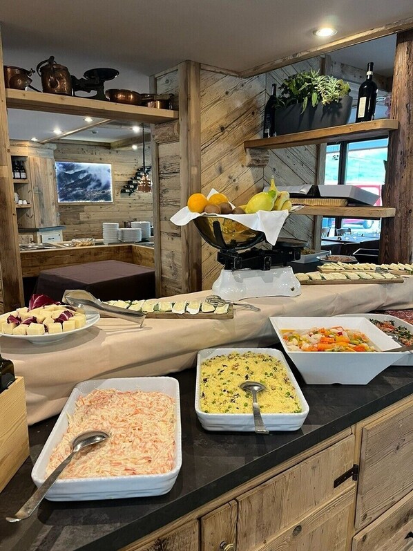 Un esmorzar buffet amb plats variats, una màquina de gofres i una presentació de fruita.