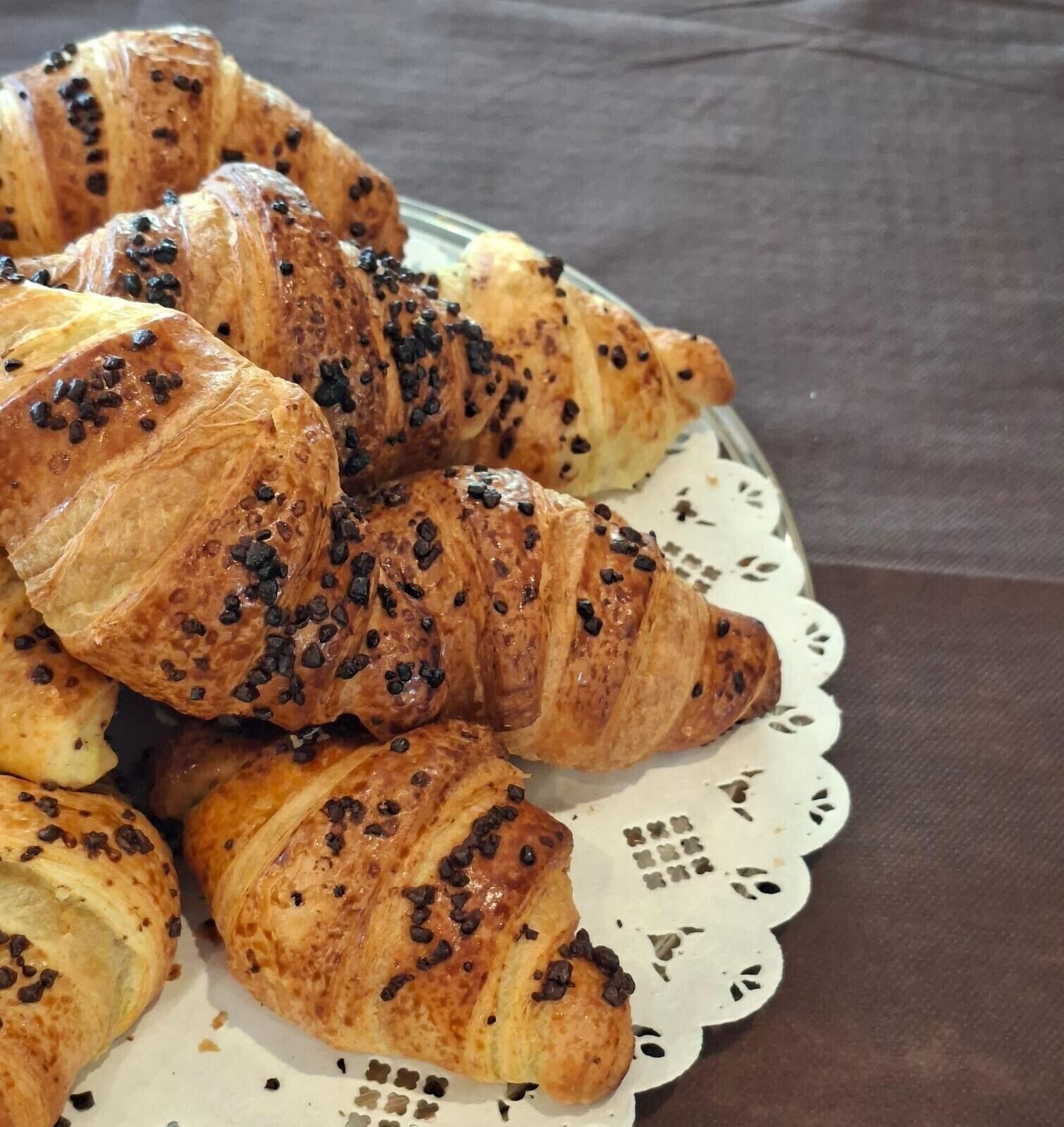 Un piatto di croissant con gocce di cioccolato su un elegante sottotavola in pizzo.