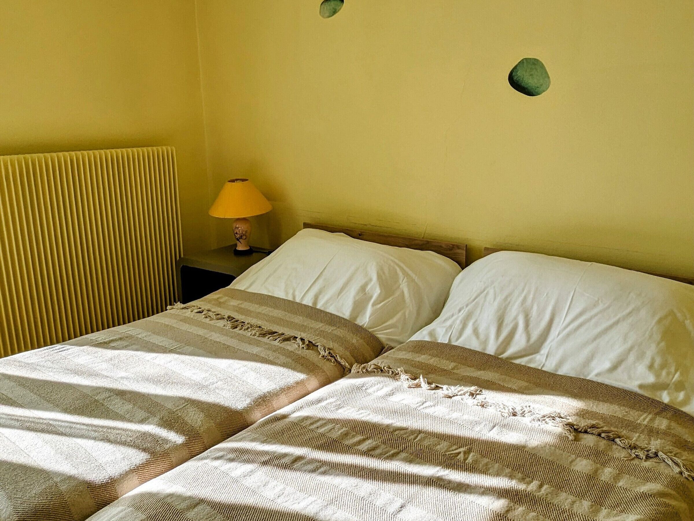 Et værelse med to senge, et natbord med lampe og en radiator.