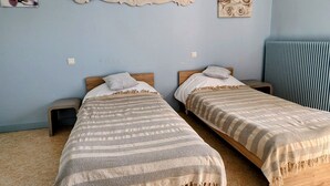 A room with two single beds, a decorative wall piece, and a radiator. - Cozy gîte in Mécrin - 10 guests (Mécrin)