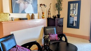A room with two black chairs, a small round table, a large framed picture on the wall, a dark-colored dresser, and a potted plant. - Cozy gîte in Mécrin - 10 guests (Mécrin)