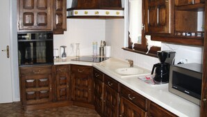 A kitchen with wooden cabinets, a built-in oven, a sink, and a microwave.