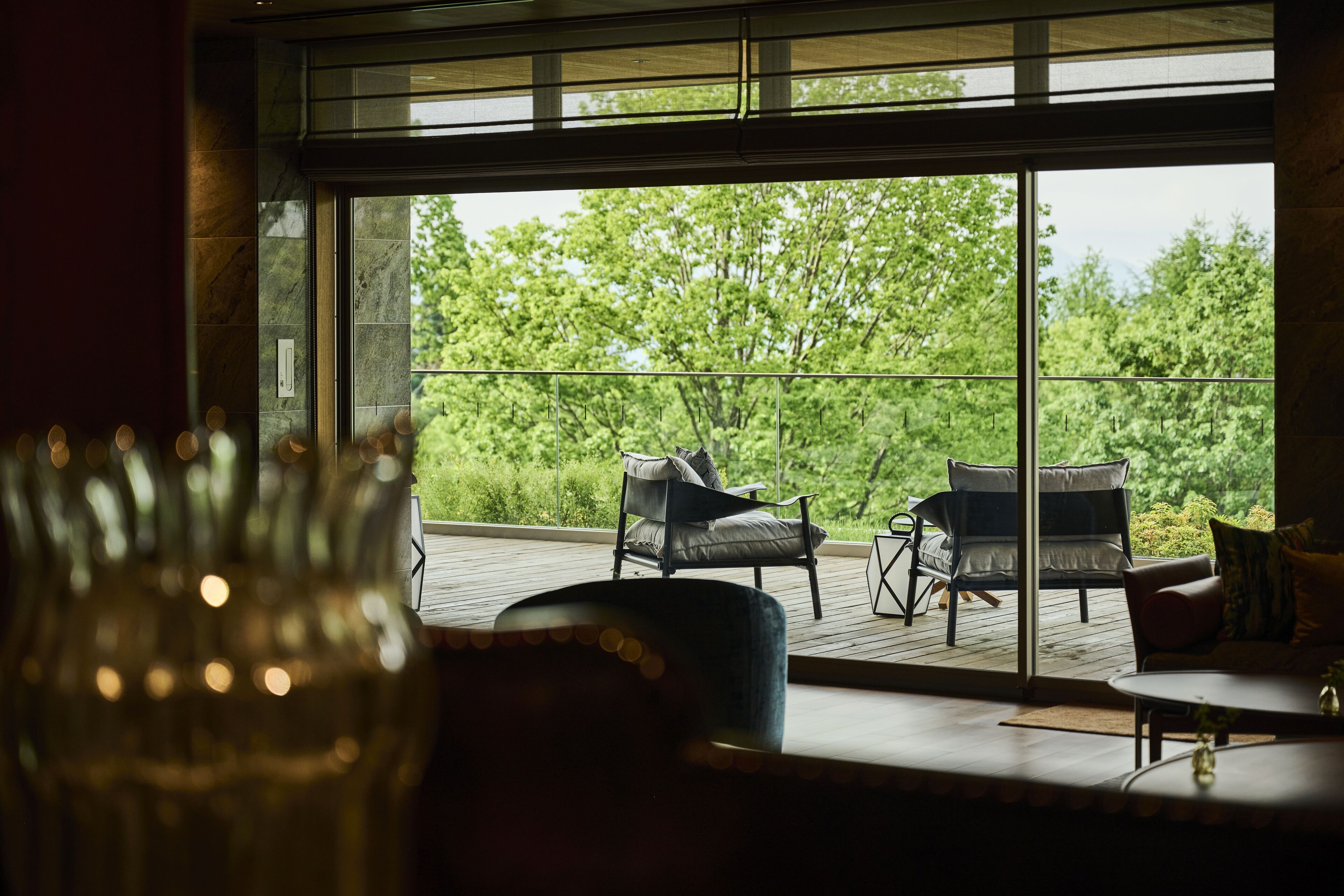 A room with a large window overlooking a deck with two chairs and a table.
