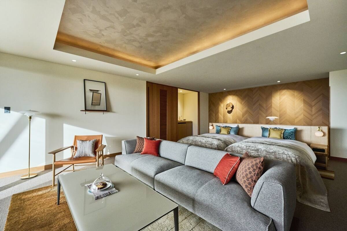 Habitació d'hotel moderna amb un llit gran, un sofà, una taula de cafè i un escriptori.