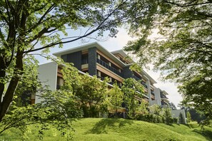 A modern multi-story building with balconies, surrounded by lush greenery and trees. - The Hiramatsu Karuizawa Miyota (Miyota)