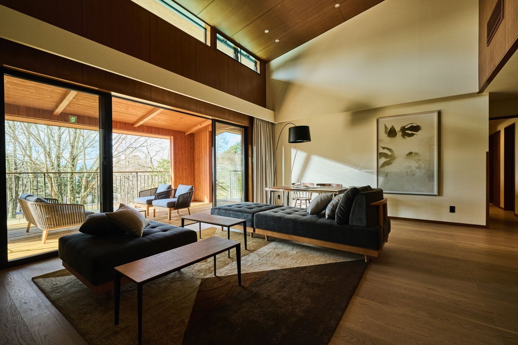 A spacious living area with a large sofa, a coffee table, and a balcony with outdoor seating.