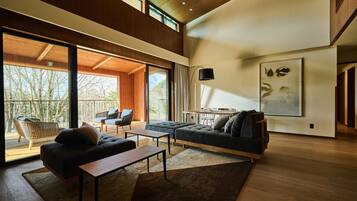 A spacious living area with a large sofa, a coffee table, and a balcony with outdoor seating.