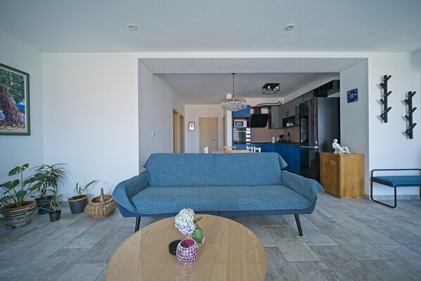 A modern living room with a blue sofa, a wooden coffee table, and a dining area in the background. - Dream vacation apartment Postira (Postira)