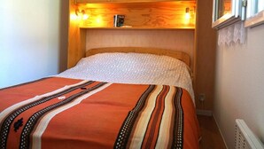 Ein Schlafzimmer mit einem hölzernen Kopfteil, einem Bett mit einem gemusterten Bettüberwurf und einem Fenster mit Blick.