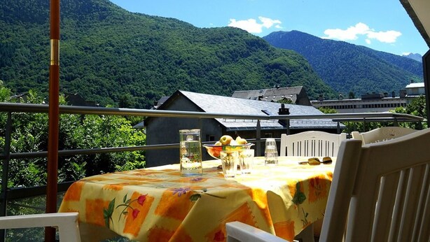 Ein Tisch im Freien mit Blick auf die Berge, einem weißen Sonnenschirm und einem Stuhl.