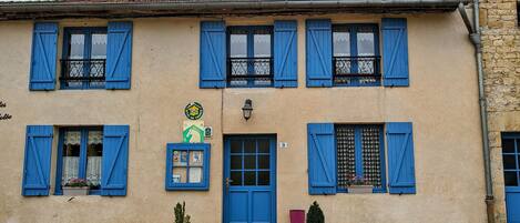 A building with blue shutters, a green sign, and a number 9 on the door.