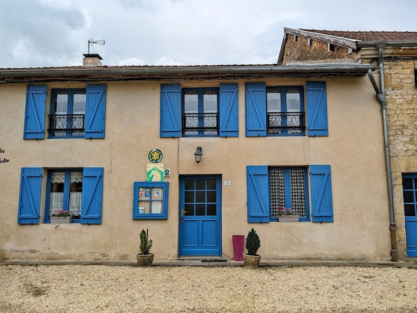 A building with blue shutters, a green sign, and a number 9 on the door.