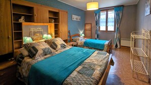 Un dormitorio con dos camas, un armario de madera y una estantería metálica.