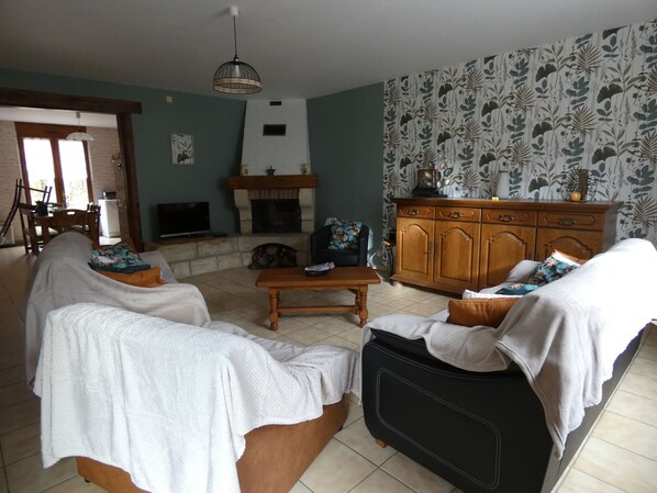 Una sala de estar con chimenea, comedor y papel tapiz estampado.