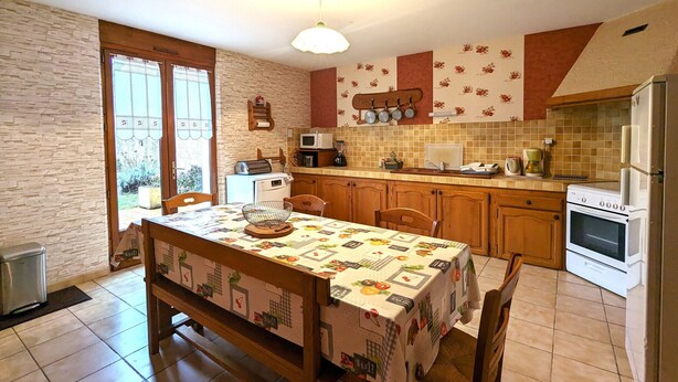 Una cocina con una mesa de comedor, sillas, un refrigerador, una estufa y un microondas.