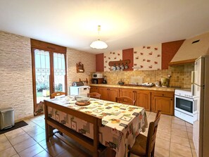 Una cocina con una mesa de comedor, sillas, un refrigerador, una estufa y un microondas.