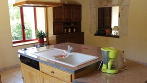 Una cocina con un lavamanos, armarios, una ventana y una licuadora sobre la encimera.