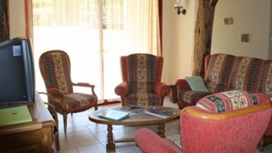 Una sala de estar con televisor, dos sillones estampados, un sofá y una mesa de centro.