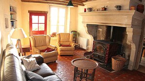 Una sala de estar acogedora con chimenea, sofá de cuero y suelo de baldosas.