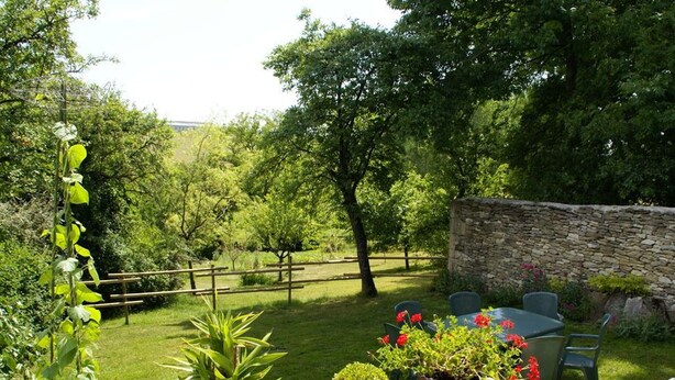 Un jardín con muro de piedra, cerca de madera y plantas en macetas.