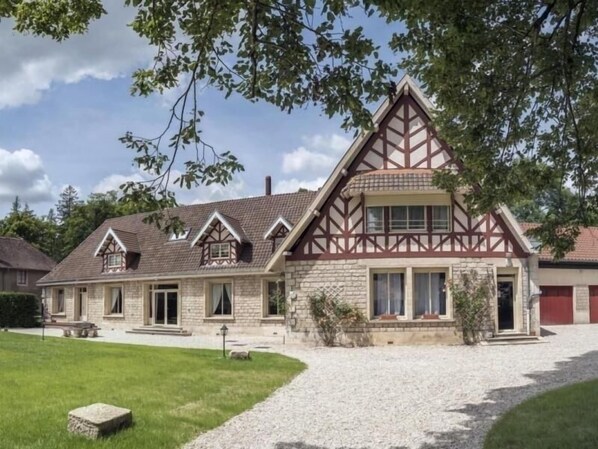 A traditional half-timbered building with a stone facade, multiple windows, and a gravel driveway. - Spacious Gîte for 12 with Fireplace & Garden, Opposite Thillombois Castle (Thillombois)