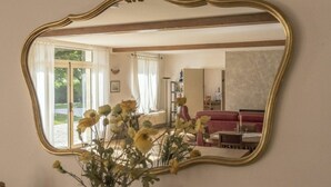 Une pièce avec un grand miroir, un vase rempli de fleurs et un canapé rouge.