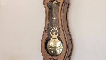 Un reloj de pie alto y ornamentado, con un espejo redondo grande en la parte inferior.