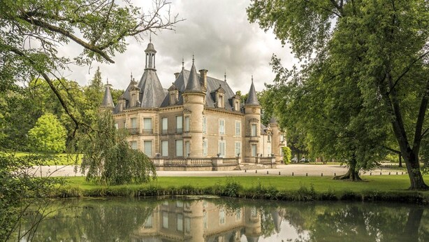 Un grand bâtiment historique doté de nombreuses tours et dont l’image se reflète dans l’eau.