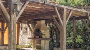 Une construction rustique en plein air, dotée d’un four en pierre, de poutres en bois et d’un mur de pierres.