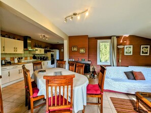 Une pièce chaleureuse et bien éclairée, avec une table à manger, des chaises, un canapé et un lit.