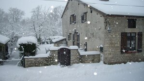 Un bâtiment en pierre avec un toit enneigé et une cheminée.