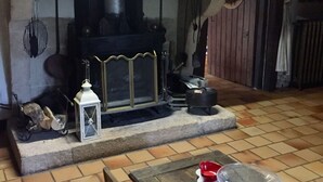 Une cheminée agrémentée d’un manteau décoratif, une lanterne et une bouilloire posées sur le foyer.