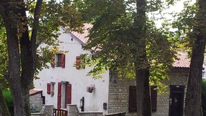 Un bâtiment blanc avec des volets rouges, une entrée en pierre et un banc devant.