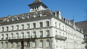 A large, historic building with a symmetrical facade, multiple windows, and a prominent tower.