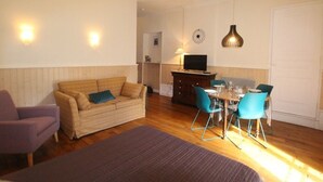 A cozy room with a bed, a sofa, a dining table with chairs, and a TV.