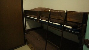 A bunk bed room with a wooden headboard, a door, and a light switch on the wall.