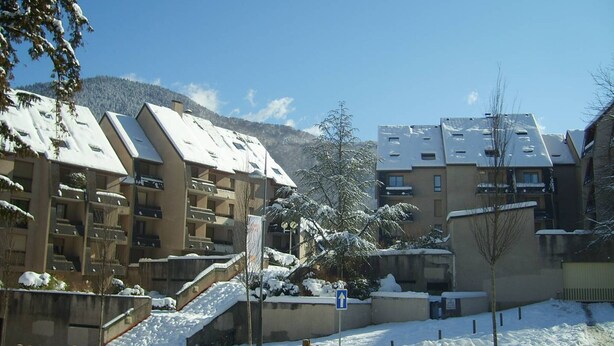 A snow-covered residential area with multi-story buildings, a staircase, and a clear sky.