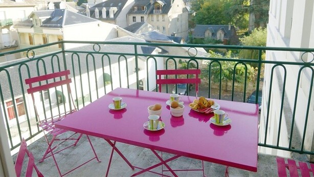 A balcony with a pink table set for two, surrounded by green metal railings. - Central Apartment near Spa, 2 Bedrooms, Sleeps 6, Parking Included (Bagnères-de-Luchon)