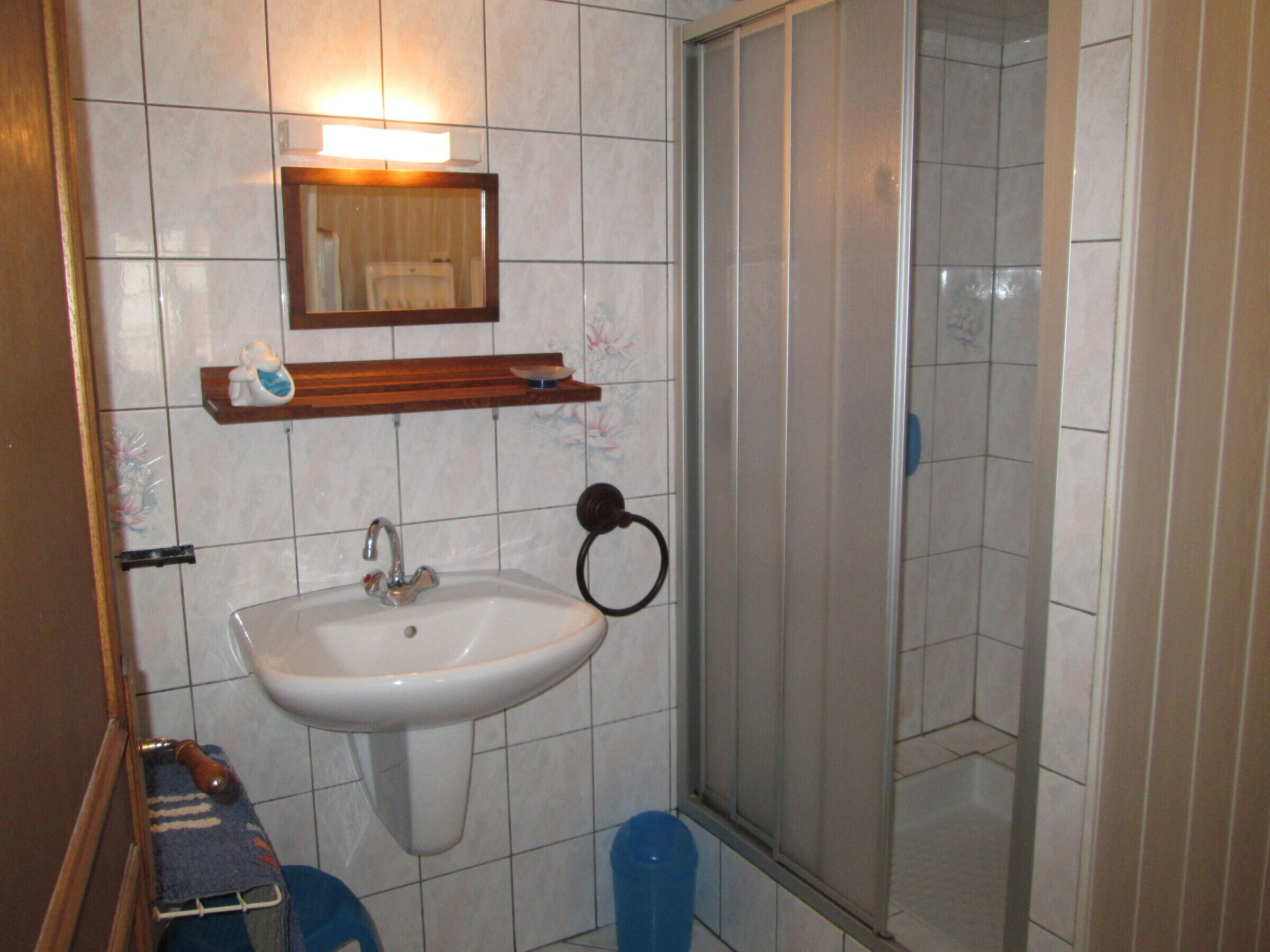 Un bagno con lavandino, specchio e doccia.