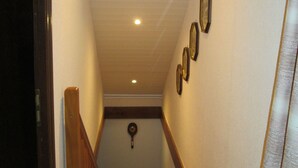 A narrow hallway with a wooden handrail, a ceiling with recessed lighting, and several framed pictures on the wall. - Charming Rural Retreat with Modern Amenities near Verdun – Pets Welcome! (Bréhéville)