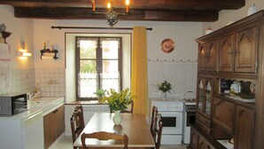A kitchen with a dining table, chairs, a stove, and cabinets. - Charming Rural Retreat with Modern Amenities near Verdun – Pets Welcome! (Bréhéville)