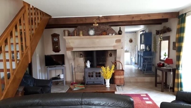A cozy living room with a fireplace, a wooden staircase, and a television.